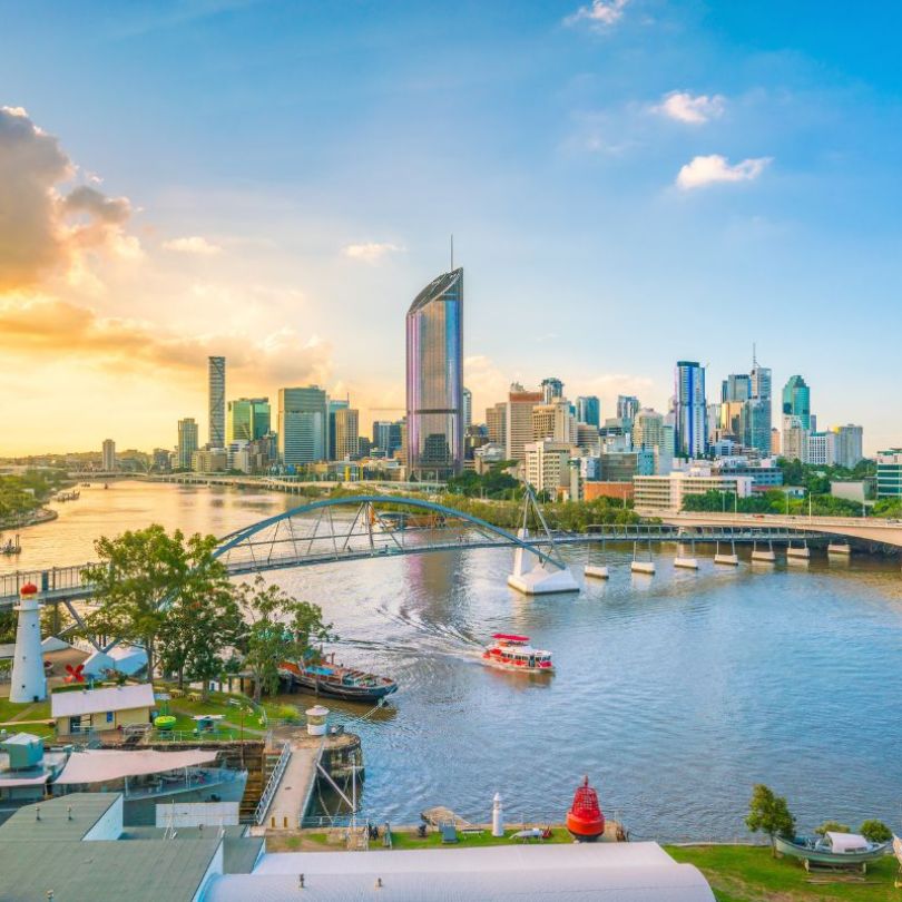 Brisbane city skyline and Brisbane River at twilight. Partly cloudy sky with a ferry in the river below. 