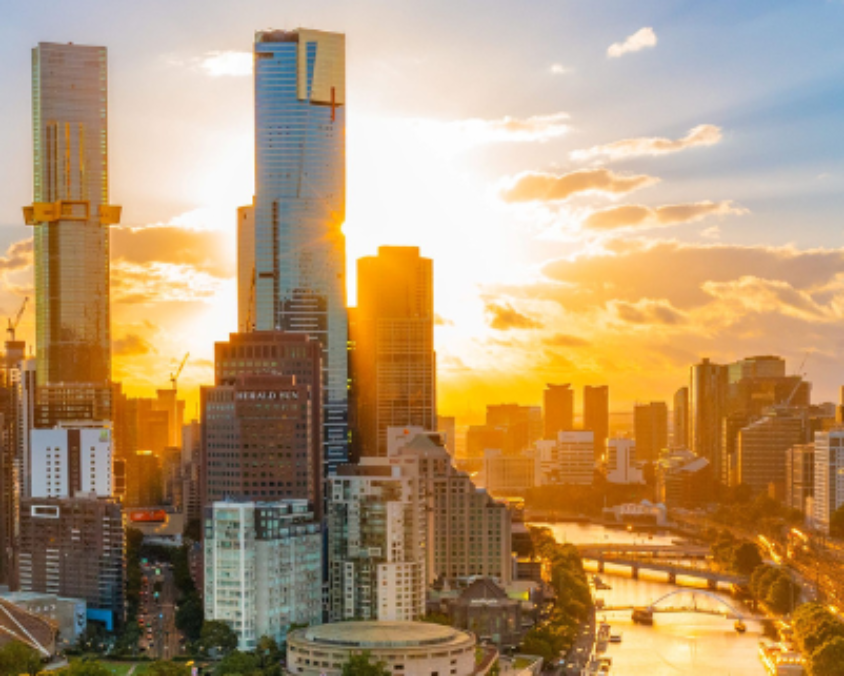 Melbourne cityscape at sunset with skyscrapers, Yarra River, and bridges under golden light.